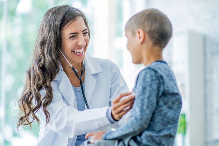 Female doctor checking boy's chest.