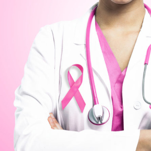 A female physician wearing a pink ribbon along with pink scrubs beneath her lab coat, and a pink cord on the stethescope around her neck