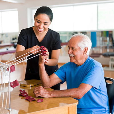 Male occupational therapy patient using equipment assisted by female therapist