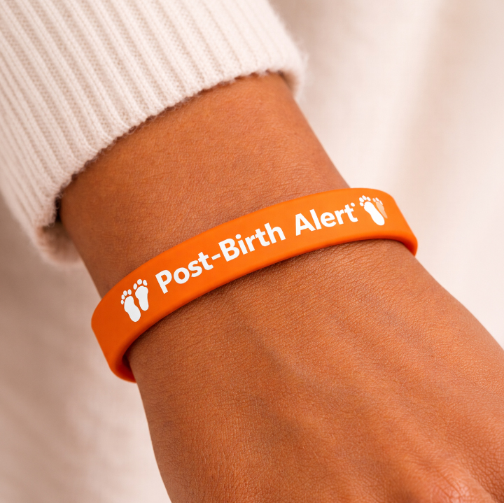 A woman's wrist is shown wearing an orange Post-Birth Bracelet