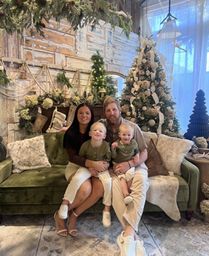 Family photo in front of Christmas tree and decor, including dad, mom, and two small children