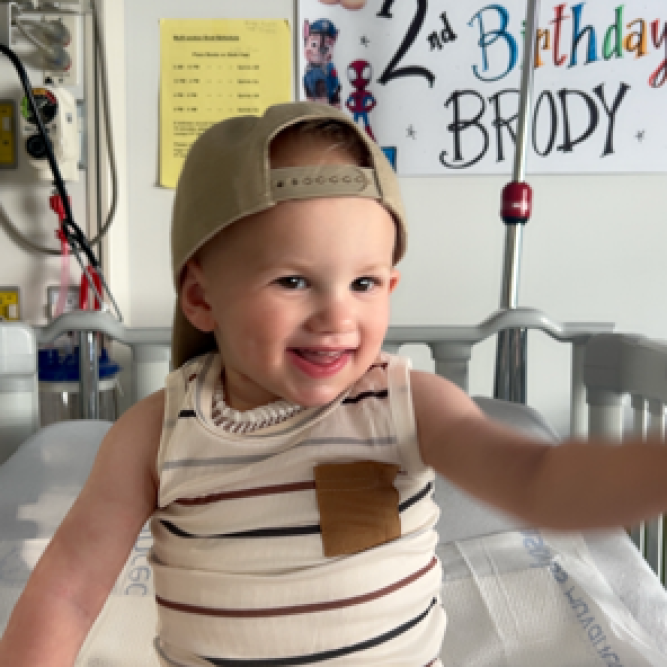 Small male child in hospital room wearing sleeveless t-shirt and backwards baseball hat