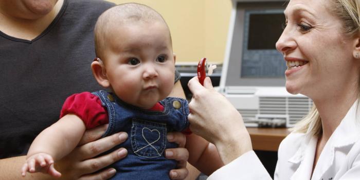 Mom holding baby with audiologist