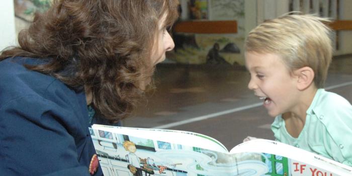Volunteer reading a book to a boy