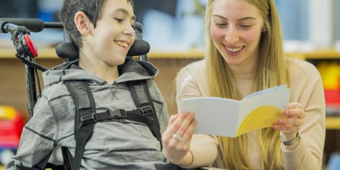 Volunteer reading to boy in wheelchair