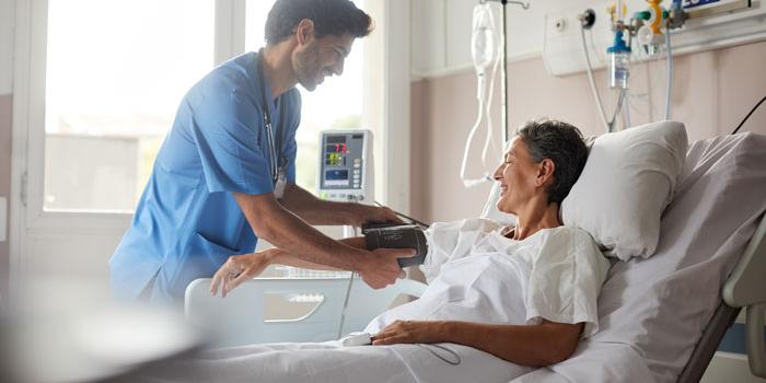 Man tending to woman patient laying in bed smiling