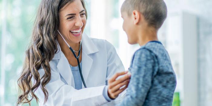 Female doctor checking boy's chest.