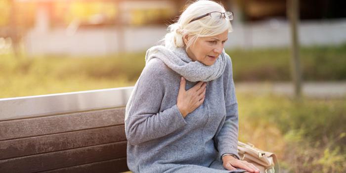 woman holding chest outside on park bench.