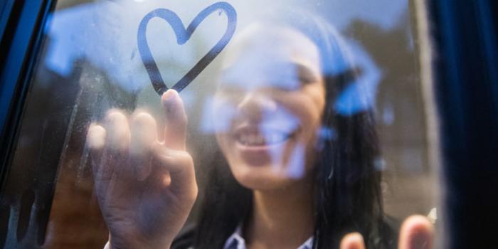 woman drawing a heart on a cold window.