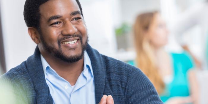 man sitting with hands clasped together