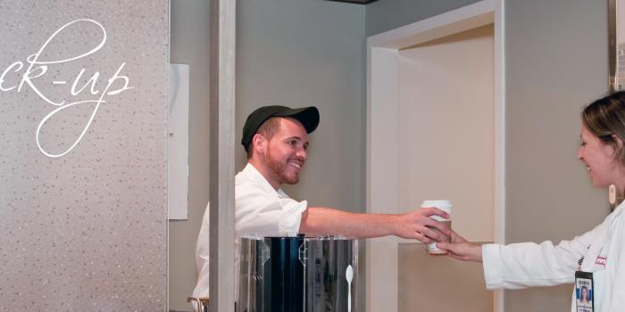 man in cafe handing drink to female doctor