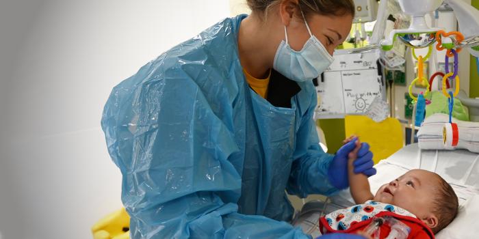 nurse holding baby's hand in NICU