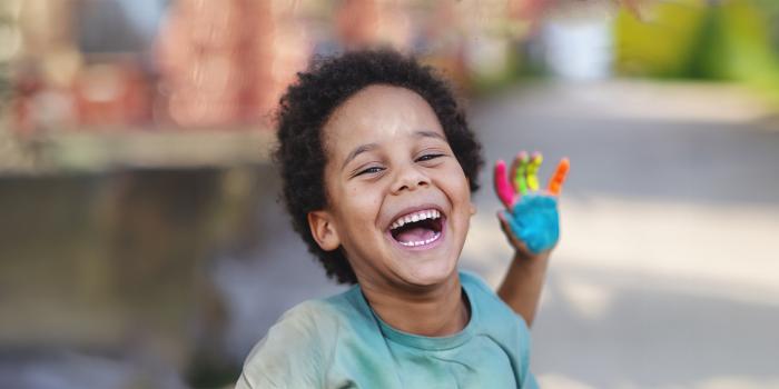 smiling boy with colorful paint on his hand 