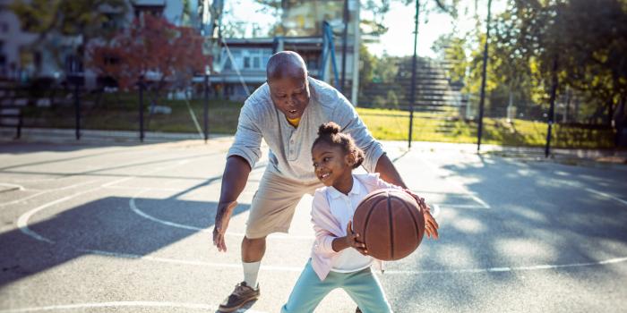 A grandfather joyfully plays basketball with grandaughter after knee replacement.