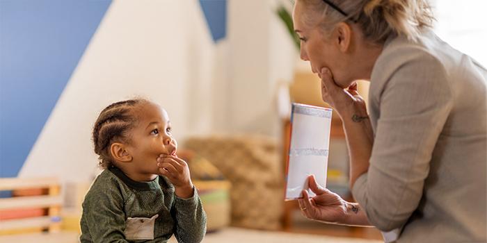 Little boy squeezing mouth during speech therapy with rehab staff