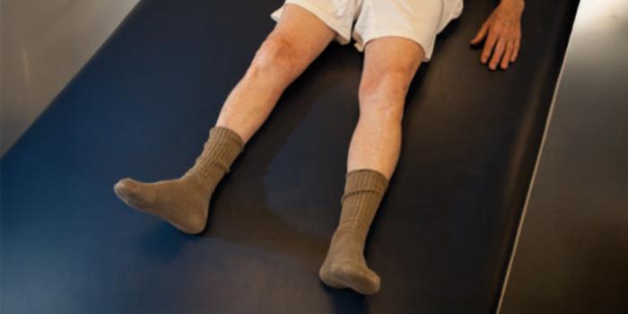A person's legs are outstretched. Legs are shown sliding out to side, with toes pointed up and knees straight. Legs are then slid back to starting point to perform hip abduction and adduction.