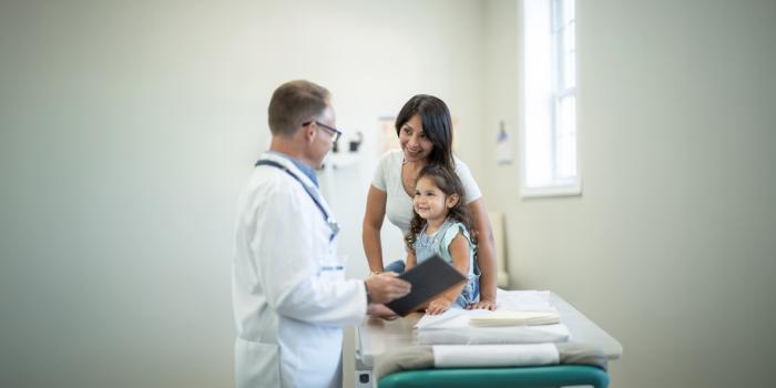 A mother and daughter meet with a pediatrician in the exam room.